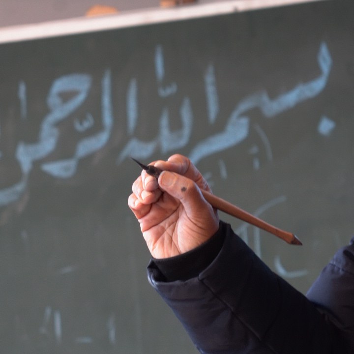 Hand holding a traditional reed pen