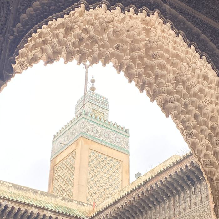 A minaret framed by a carved muqarnas arch in Fez
